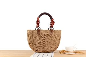 Detailed shot of a woven straw handbag with dark brown wooden beads and a round handle