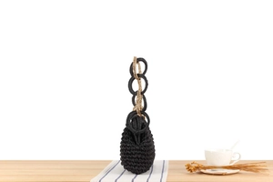 Detail of black woven handbag with gold metallic handle on an aesthetic cafe table