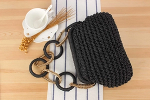Detail of black woven handbag featuring unique chunky gold and black chain strap