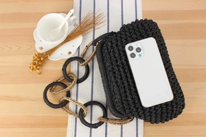 Detail of black crochet shoulder bag with chunky gold chain strap and phone size reference
