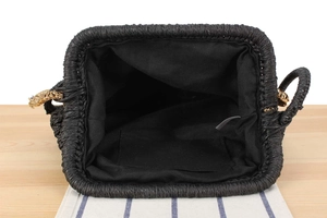 Detailed top view of black woven straw bag interior with lining and inner pocket