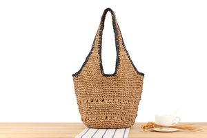 Close-up of woven straw tote bag with black trim detailing and natural fiber texture