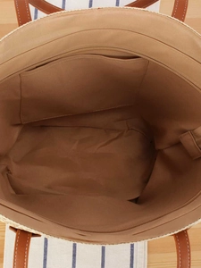 Large hand-woven straw tote bag showing internal lining and metal zipper closure