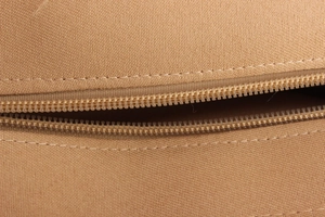 Close-up of the durable brown canvas material and precise zipper stitching on the bag