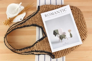 Detail of a straw tote bag with black trim accents and romantic vacation styling
