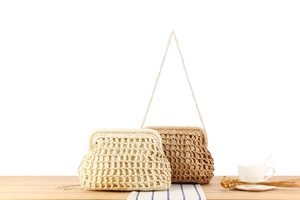 Detailed close-up of woven dumpling bags in beige and tan with gold chain straps