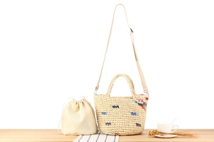 Detailed view of handmade woven straw bag with colorful accents and drawstring inner pouch