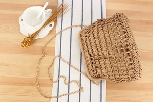 Detail of woven mesh bag with fabric lining and gold metal chain on a rustic wooden table