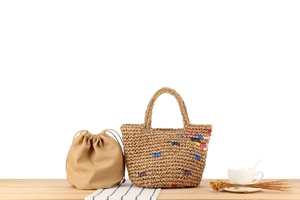 Detail of handmade woven straw tote with colorful accents and canvas drawstring inner bag