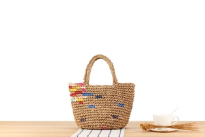 Detail of hand-woven straw tote with colorful stripes on a bright wooden surface