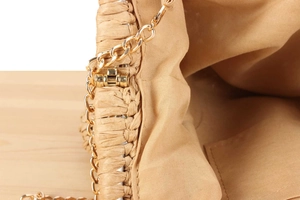 Detail shot of handwoven straw bag featuring golden metal chain and secure push lock