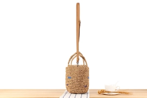 Detailed close-up of handmade woven straw bucket bag texture with colorful accents