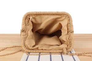 Top view of woven straw bag with fabric lining, inner pocket, and gold chain strap