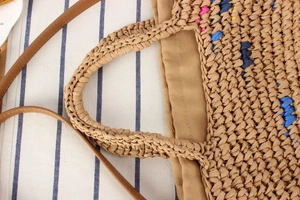 Top view of handmade woven straw bag featuring colorful patterns and brown leather strap
