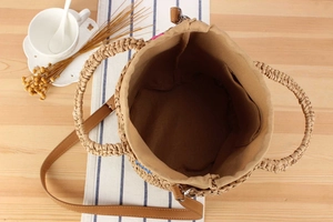 Detailed interior of straw bucket bag with fabric lining and leather shoulder strap