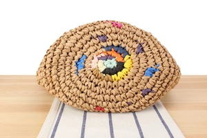 Close-up of handmade woven bag with colorful bohemian circular pattern on wooden table