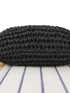 Handwoven black straw bag with textured fiber detail on a blue striped napkin