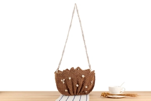 Detail of raffia woven bag featuring pearls, shells, and elegant gold chain strap