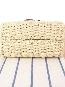 Close-up of beige woven straw tote bag featuring dense texture and secure metal clasp
