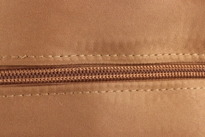 Macro shot of durable nylon zipper and double-stitched seams on brown raffia handbag