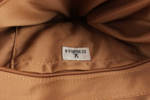 Detail shot of the durable polyester lining and branded zipper pocket of the raffia bag