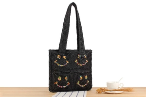 Detail of hand-woven black tote bag with colorful beaded smiley face patterns on the side