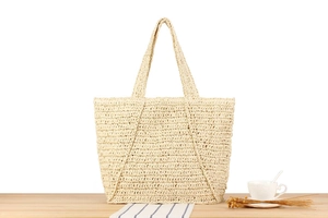 Detailed view of handmade woven straw tote bag with wide handles and natural texture