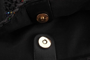 Detail of black woven bag featuring colorful beads and gold magnetic closure