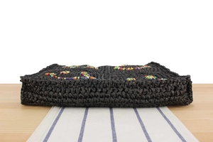 Detail of black woven bag showing handmade raffia texture and colorful beaded patterns