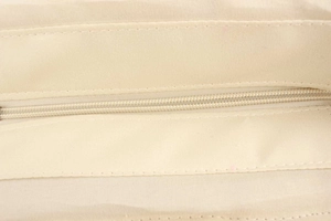 Detailed close-up of zipper closure and precise stitching on beige woven tote bag
