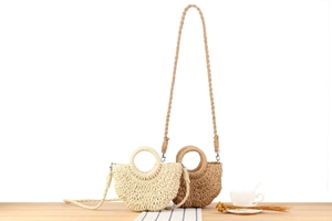 Detail of semi-circular straw woven bags in beige and brown with circular handles