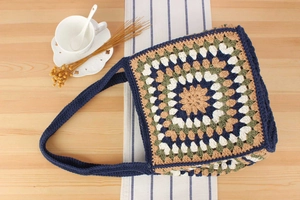 Close-up of handmade crochet tote bag with colorful granny square patterns and woven strap