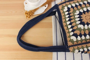 Detail of crochet shoulder bag with colorful floral pattern and wide woven strap