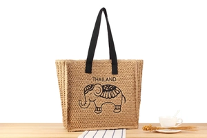 Close-up of woven straw handbag featuring Thailand elephant print and black handles