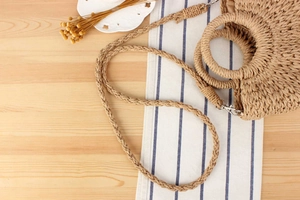 Detail of hand-woven straw bag with round handles and detachable shoulder strap