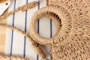 Detail of woven straw handbag texture with round handle and silver metal lobster clasp
