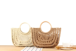 Detail of woven handbags with circular handles in cream and brown on a wooden desk