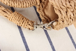 Macro detail of silver metal lobster clasp and hand-woven natural straw strap on casual bag