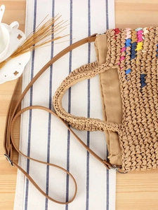 Handwoven straw tote bag with colorful accents and leather strap for beach vacations