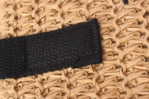 Detailed macro view of woven straw bag texture with black fabric strap stitching