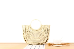 Detail of handmade woven straw bag with hollow grid pattern on a wooden table