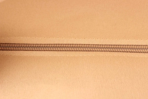 Detailed close-up of a durable nylon zipper on a premium tan canvas beach bag