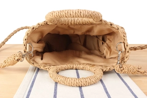 Detail view of woven straw bag showing natural texture, round handle, and drawstring lining