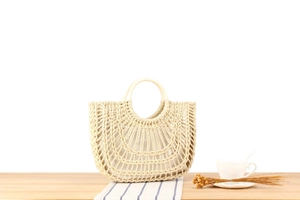 Close-up of hollowed-out straw woven handbag with round wooden handles and fabric lining