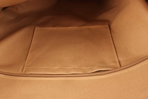 Detailed interior of woven beach bag showing fabric lining with open pocket and zipper