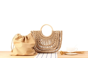 Macro shot of hand-woven straw bag with round wooden handles and drawstring canvas liner