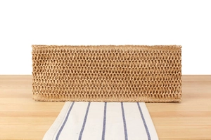 Detail of hand-woven straw tote bag with intricate hollow patterns on a wooden surface