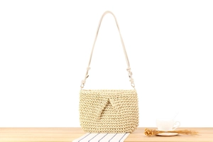 Detailed macro view of cream woven shoulder bag with leather strap and gold hardware
