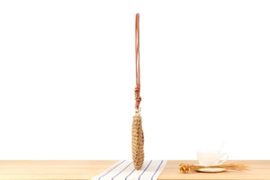Detailed close-up of woven straw shoulder bag with elegant brown leather knot strap