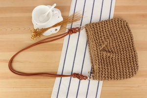Macro detail of natural straw texture and brown leather straps on the woven tote bag